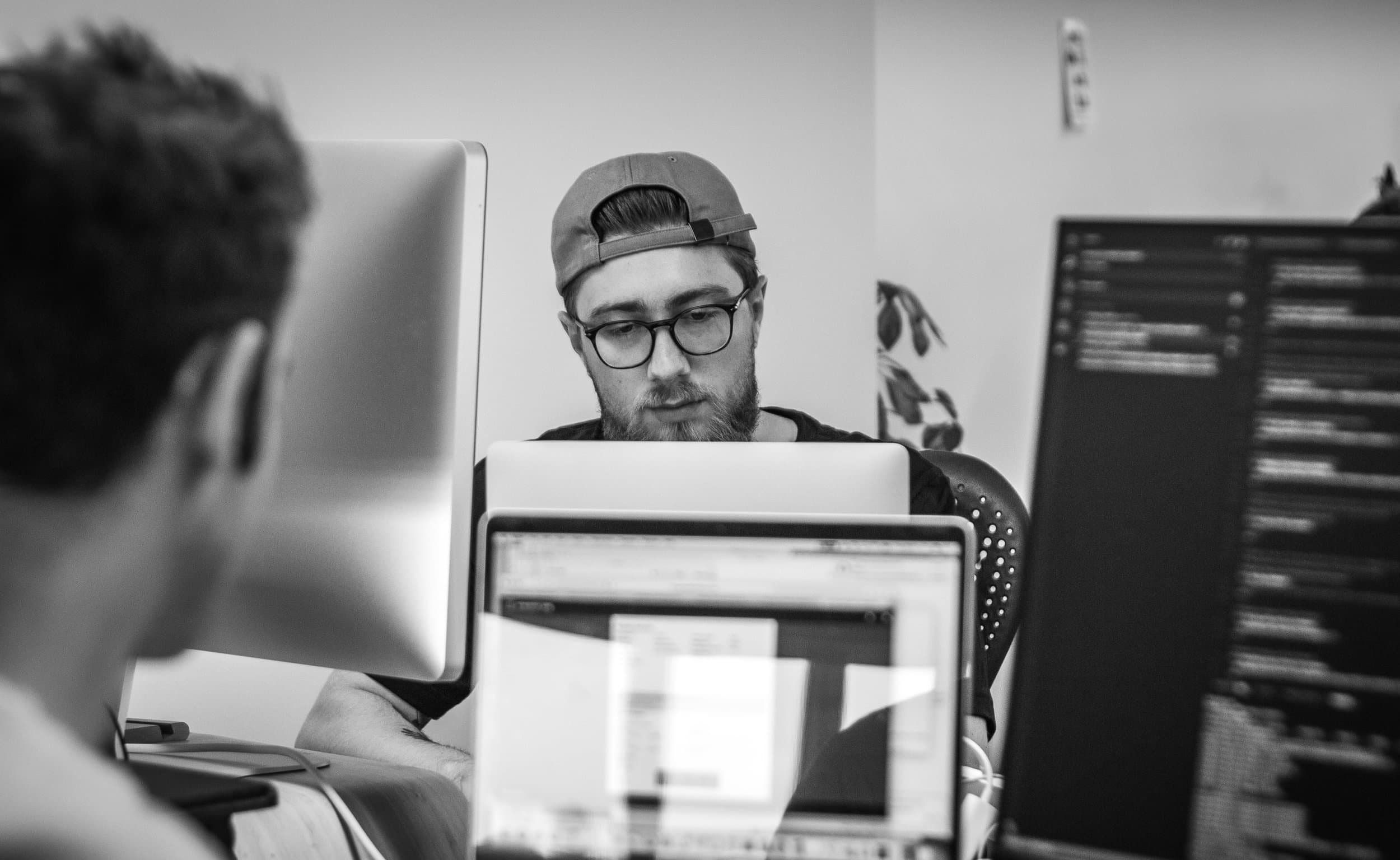 Black-and-white photo of developer (Jamie) behind multiple monitors