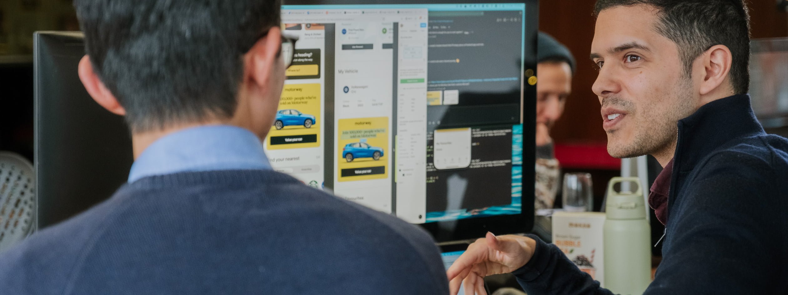 Developers deep in discussion around a screen showing work in progress