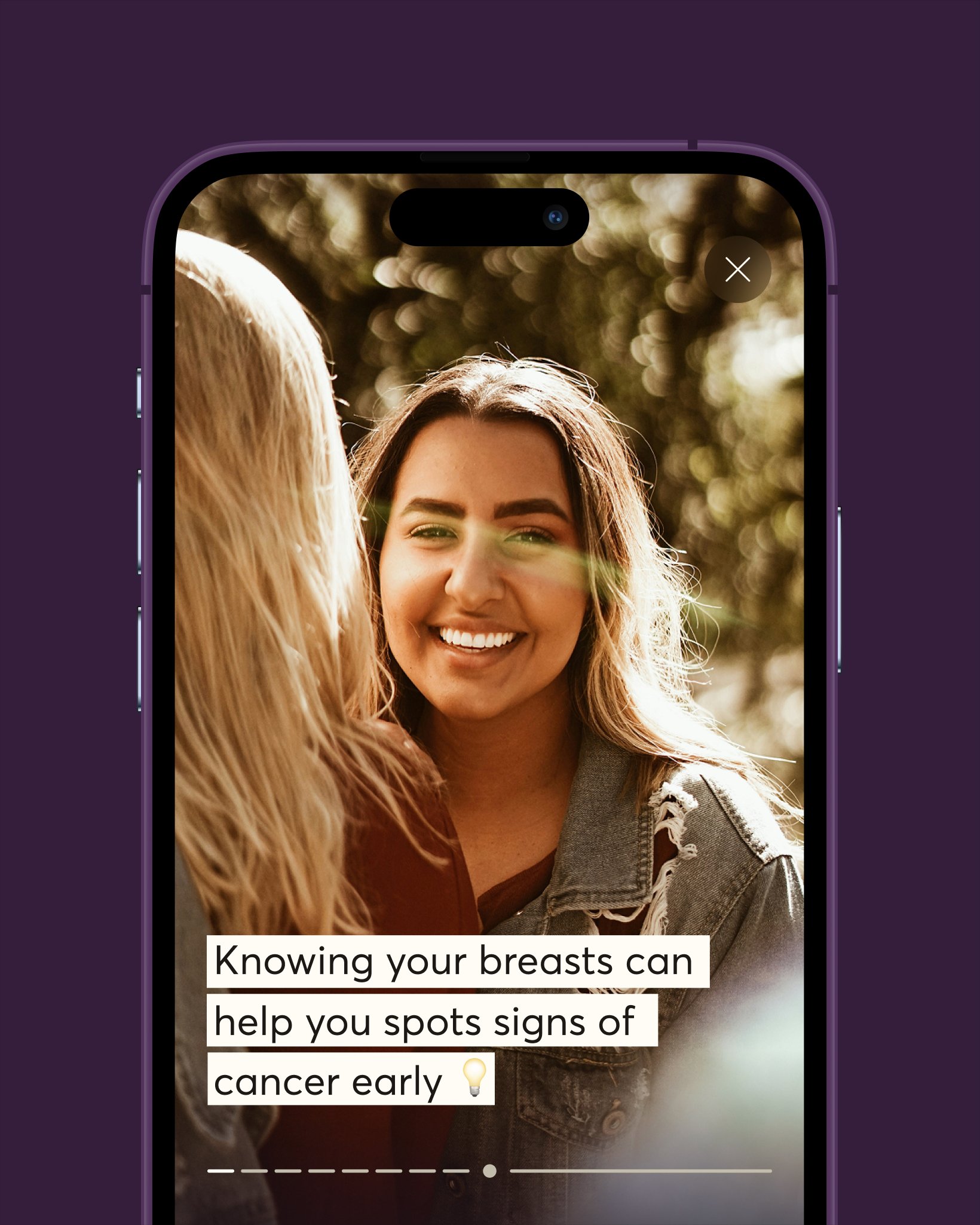 An iPhone displaying a 28X health education slide with a smiling woman in a denim jacket and the caption 'Knowing your breasts can help you spot signs of cancer early'.