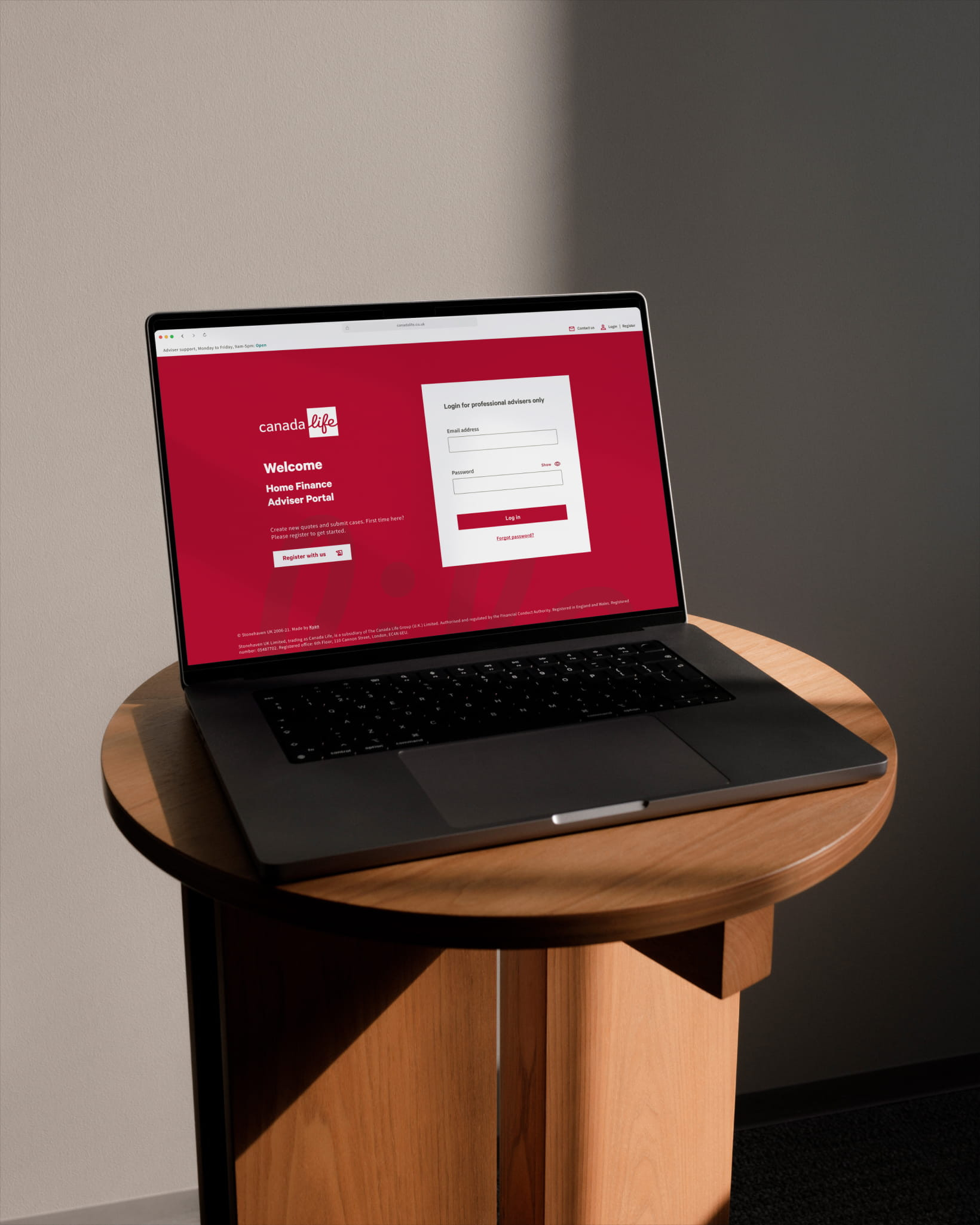A laptop on a wooden pedestal table displaying the Canada Life Home Finance Adviser Portal login screen in a red and white interface.
