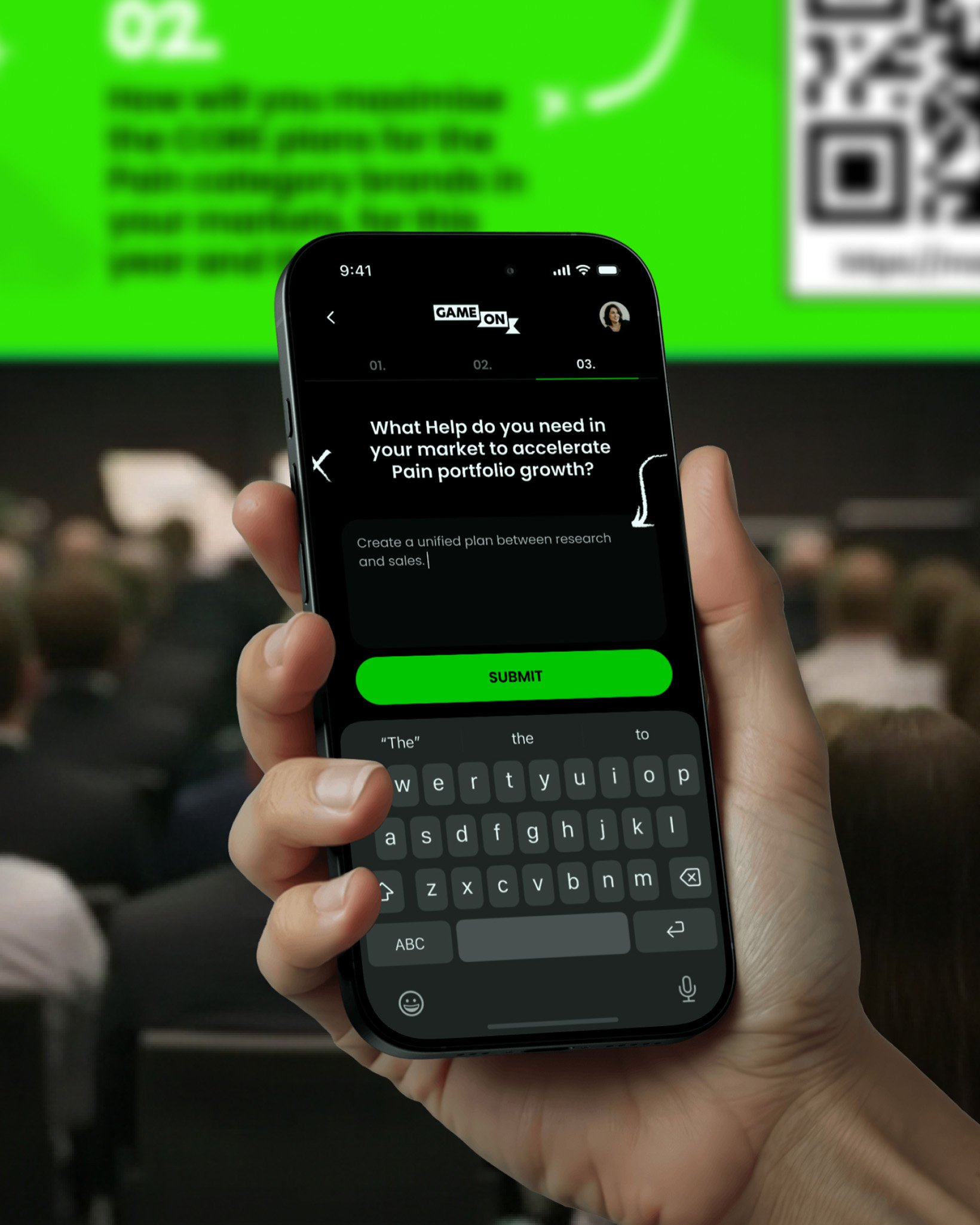 A hand holding a smartphone displaying the Game On input screen, with a question about accelerating pain portfolio growth and a green submit button.