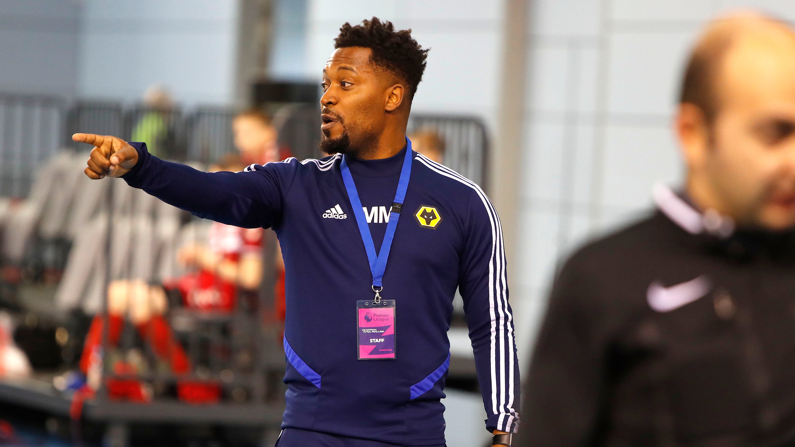 Football coach pointing and giving instructions to players on the pitch