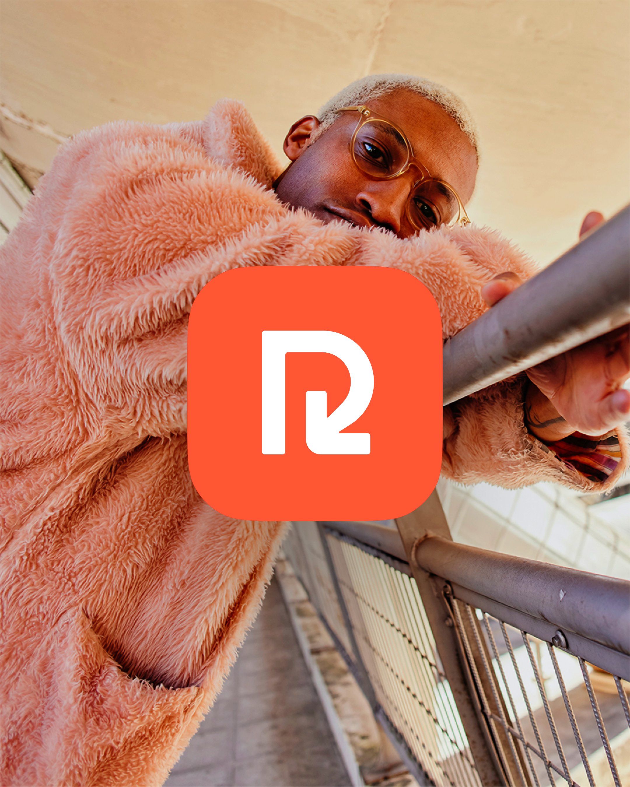 A person in a pink faux-fur coat leaning over a metal railing, with the orange ReShop logo centred prominently in the foreground.