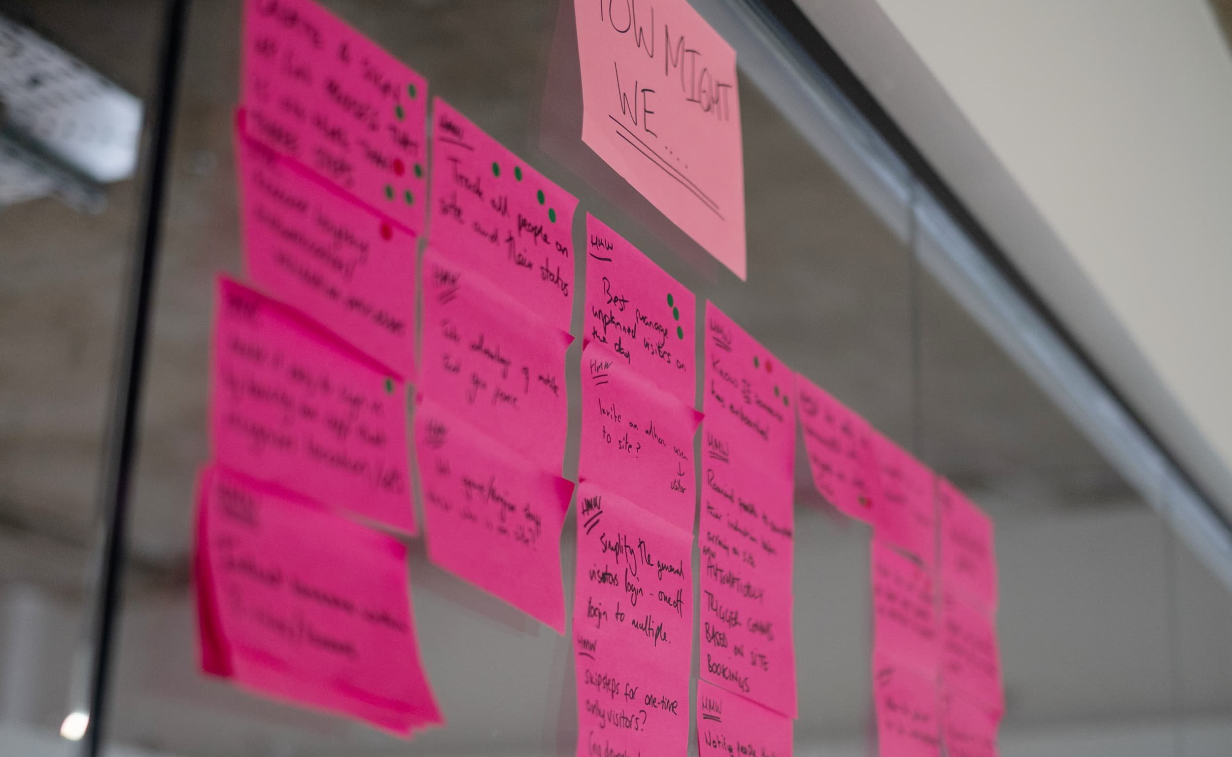Bright pink sticky notes with ideas on a glass wall